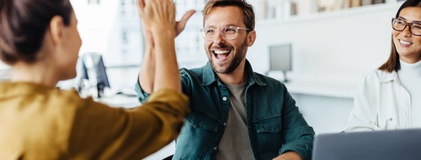 Two business people celebrating the success of outsourced B2B marketing with a high five